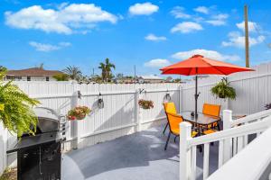 un patio con una mesa y una sombrilla roja en Tropical Paradise en Cape Coral