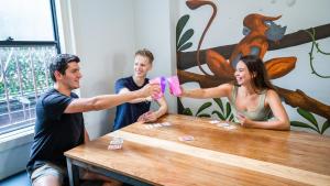Eine Gruppe von drei Personen, die Karten an einem Tisch spielen in der Unterkunft Mad Monkey Downtown in Sydney