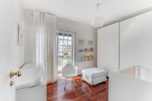 Casa da Praia في استوريل: غرفة بيضاء مع كرسي أبيض ونافذة