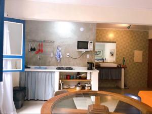 Una sala de estar con una mesa y una cocina. en Suite Charme apt 02, en Ilhabela