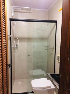 Un baño con ducha de cristal con inodoro. en Suite Charme apt 02, en Ilhabela
