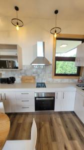 a kitchen with white appliances and a table and a window at Cabañas Krause Lodge in Puerto Varas