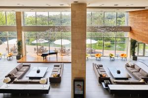 een grote lobby met banken, tafels en ramen bij Rolling Hills Hotel in Hwaseong