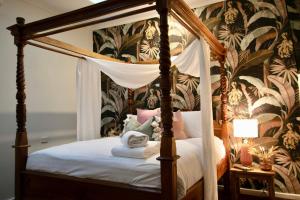 a bedroom with a canopy bed with floral wallpaper at Rústicoq B+B in Cowaramup