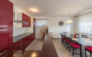 a kitchen with red cabinets and a table and chairs at Family-friendly apartments with swimming pool Stara Vas, Pag - 21031 in Pag