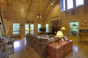 a living room with a couch and a fireplace in a log cabin at Go Fish- Fightingtown Creek Frontage in McCaysville