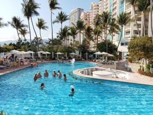 a group of people in a swimming pool with palm trees at Ocean Pacific appartment in Acapulco