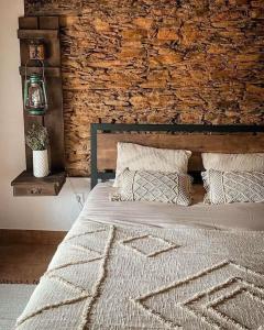 a bed in a bedroom with a brick wall at Monte da Parreira in Cabeça de Carneiro