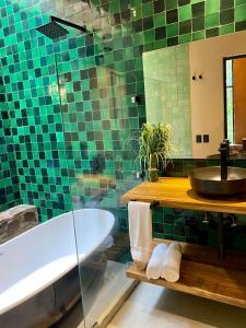 baño de azulejos verdes con bañera y lavamanos en Casa Patio, en San Sebastián del Oeste