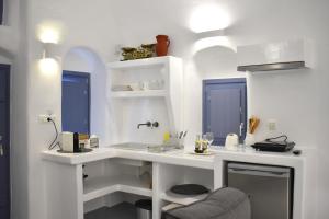 - une cuisine blanche avec évier et fenêtres bleues dans l'établissement Oinos Luxury Suites, à Foinikiá