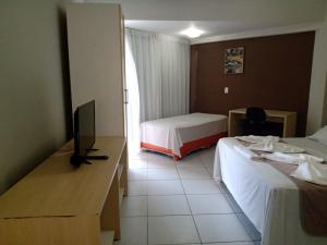 um quarto de hotel com duas camas e uma televisão de ecrã plano em Marsallis Residence Flat-EFM601 em Natal
