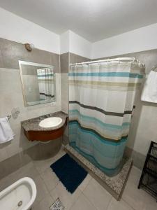 a bathroom with a sink and a shower with a shower curtain at Departamento Macrocentro amoblado (zona Sanatorio Privado) in Río Cuarto