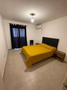 a bedroom with a yellow bed and a window at Departamento Macrocentro amoblado (zona Sanatorio Privado) in Río Cuarto