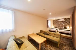 a living room with a couch and a bed at Sakura Garden Hotel in Osaka