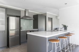 a kitchen with a white counter and bar stools at Seagreen Bach in Raglan