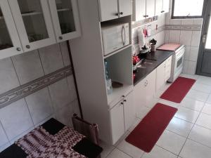 a kitchen with white cabinets and a red rug at Apt térreo com 3 qtos e 1 vaga in Poços de Caldas