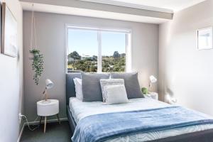 a bedroom with a bed and a large window at Seagreen Bach in Raglan