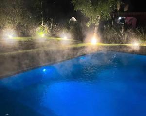 a swimming pool with blue water at night at Casa con piscina privada climatizada e iluminada en exclusivo Golf Country Club Campo de Golf de 18 hoyos Piscina cubierta climatiza del club Canchas de futbol y tenis profesionales iluminadas Recreación Infantil Market y todo tipo de servicios in Buenos Aires