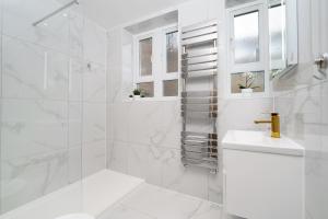 La salle de bains blanche est pourvue d'un lavabo et d'une douche. dans l'établissement Boutique Flat near O2 & Excel, à Londres
