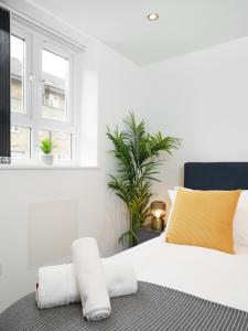 a bedroom with a bed with white sheets and yellow pillows at Boutique Flat near O2 & Excel in London