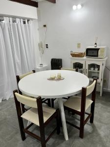 una mesa blanca y sillas en una cocina con microondas en Complejo Alberdi Depto 3 en Tandil
