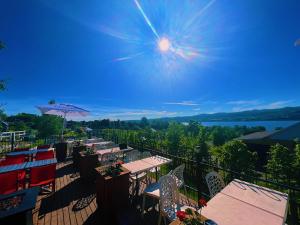 a balcony with tables and chairs and a view of the water at Auberge au Poste de Traite in Sainte-Famille