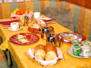 a table with plates of food on a yellow table cloth at Jolly B&B - Affittacamere in Dimaro