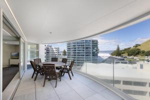 a dining room with a table and chairs on a balcony at Oceanside Marine Pde Magic in Mount Maunganui