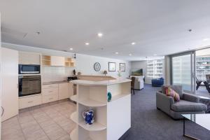 a kitchen and living room with a couch and a table at Oceanside Marine Pde Magic in Mount Maunganui