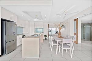 una cocina con electrodomésticos blancos, mesa y sillas en Spectacular Darwin apartment en Darwin