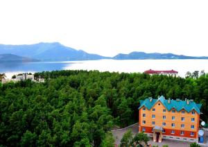 an orange building with a blue roof on a hill next to a lake at Hotel Nurlytau in Borovoye