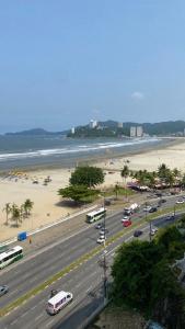 a city street with buses and a beach and the ocean at Apartamento Frente à Praia Santos in Santos
