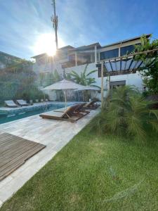 ein Haus mit einem Pool und einer Terrasse mit einem Sonnenschirm in der Unterkunft Pousada Laranja - Nova Administração in Natal