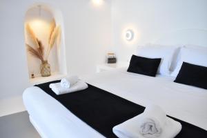 1 dormitorio con 2 camas blancas y toallas. en Oinos Luxury Suites Caldera, en Oia
