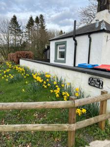 płot przed domem z żółtymi kwiatami w obiekcie Cosy country cottage in rural location w mieście Moffat
