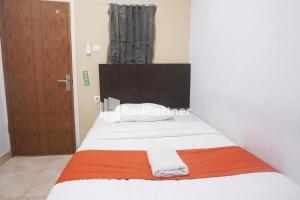a bedroom with a bed with an orange and white blanket at Tassa Homestay Syariah Mitra RedDoorz in Jambi