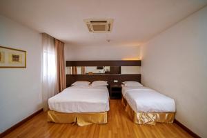 2 camas en una habitación de hotel con sábanas blancas en Uptown Chinatown, en Kuala Lumpur