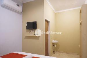 a bedroom with a tv on the wall and a bed at Tassa Homestay Syariah Mitra RedDoorz in Jambi