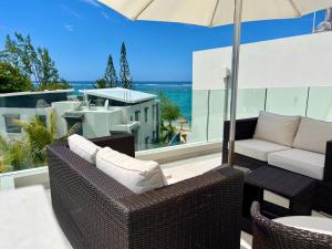 a patio with wicker chairs and an umbrella at Exclusive beachfront penthouse in Belle Mare