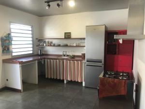 ヌメアにあるThe Hidewayのキッチン(赤と白のキャビネット、冷蔵庫付)