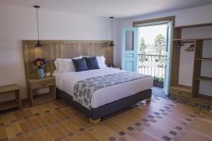 1 dormitorio con 1 cama grande y balcón en Alfahar Hotel, en Carmen de Viboral
