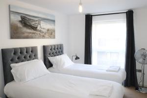 two beds in a room with a window at Garland Modern Central City Apartment London in London