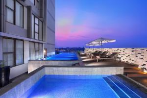 a swimming pool with an umbrella next to a building at Harper Malioboro Yogyakarta by ASTON in Yogyakarta