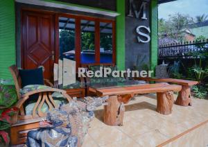 a wooden bench and a chair in front of a house at MS Hotel Pangandaran Mitra RedDoorz in Pangandaran