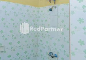 a bathroom with a shower with green clovers on the wall at MS Hotel Pangandaran Mitra RedDoorz in Pangandaran