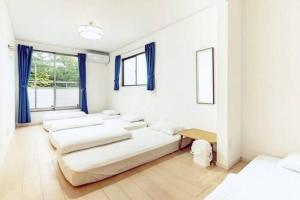 a room with four beds in it with blue curtains at 我が家inOKINAWA 私の家in沖縄 in Onna