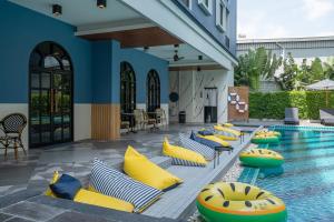 a pool with yellow and blue pillows next to a resort at Cozy Blu Suvarnabhumi in Samutprakarn