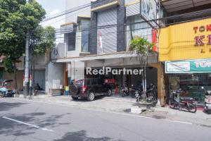 una tienda asociada roja en una calle de la ciudad con motocicletas estacionadas en frente en Crown Residence near Tugu Yogyakarta Mitra RedDoorz, en Yogyakarta