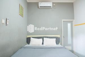 een slaapkamer met een bed met een rood randbord aan de muur bij Crown Residence near Tugu Yogyakarta Mitra RedDoorz in Yogyakarta