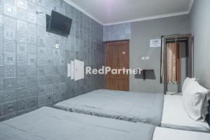 two beds in a room with a red partner sign on the wall at Crown Residence near Tugu Yogyakarta Mitra RedDoorz in Yogyakarta